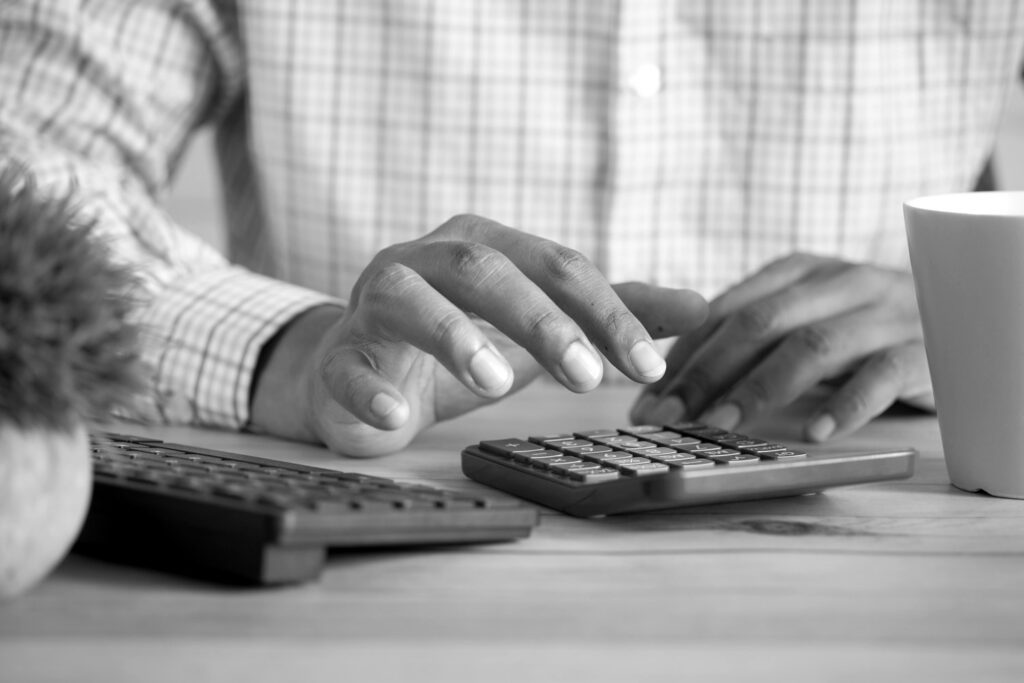 Mãos operando uma calculadora ao lado do teclado